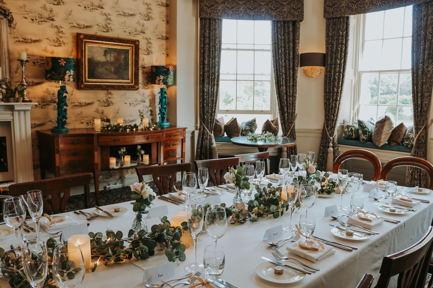 Elegant wedding reception table setting with white linens, floral centerpieces and vintage decor in historic stone room.