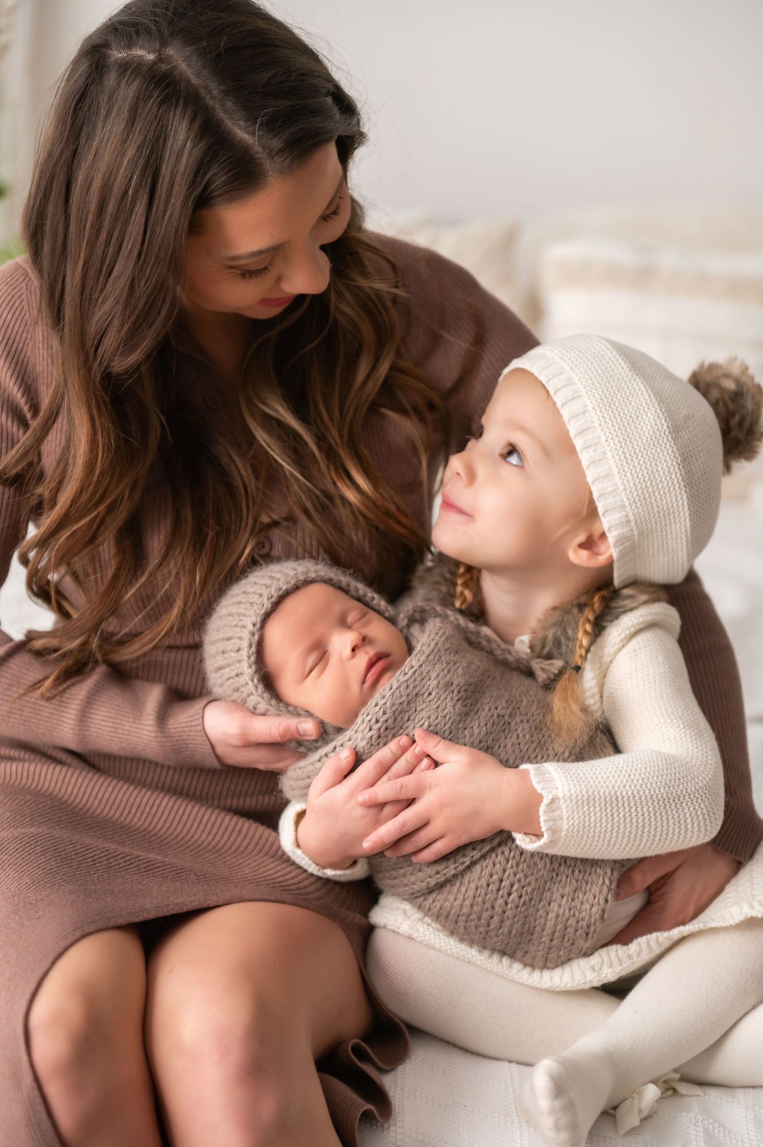 An intimate indoor family moment with small children in warm neutral tones.