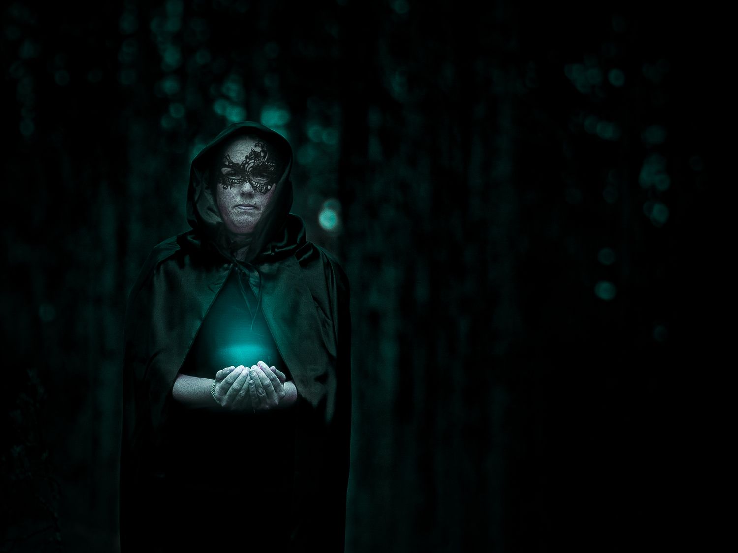 A dark and eerie forest scene with mysterious blue-green lights glowing between shadowy trees.