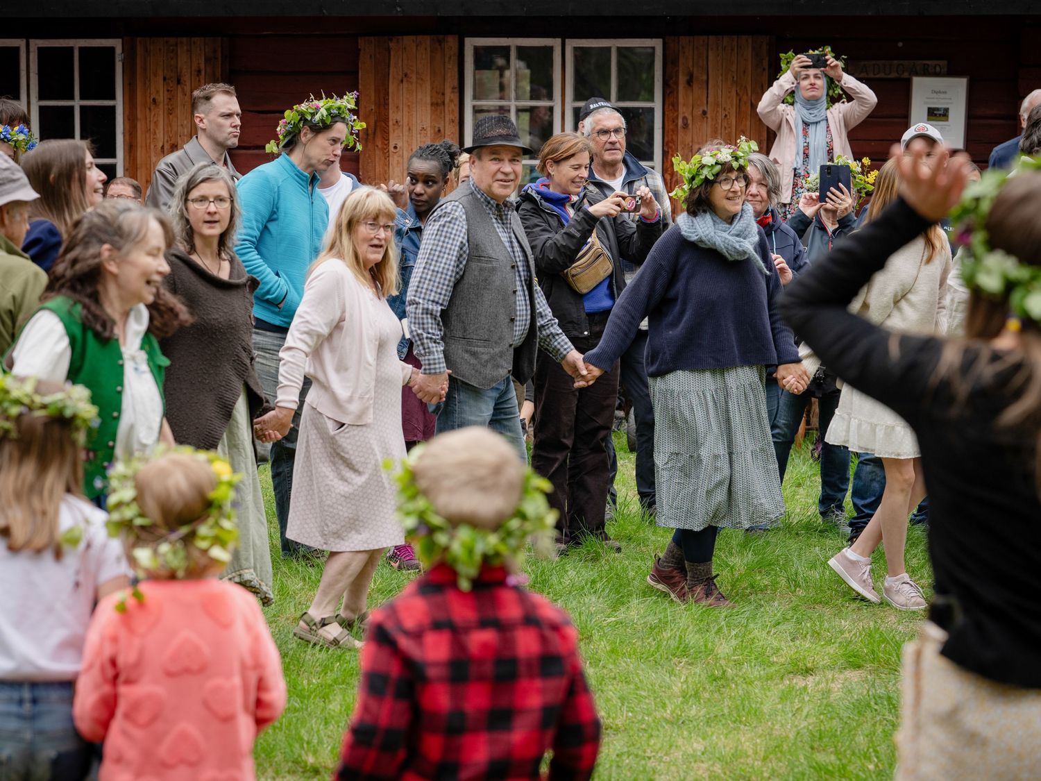 A crowd of people gather on a lawn outside during what appears to be a social event or gathering.