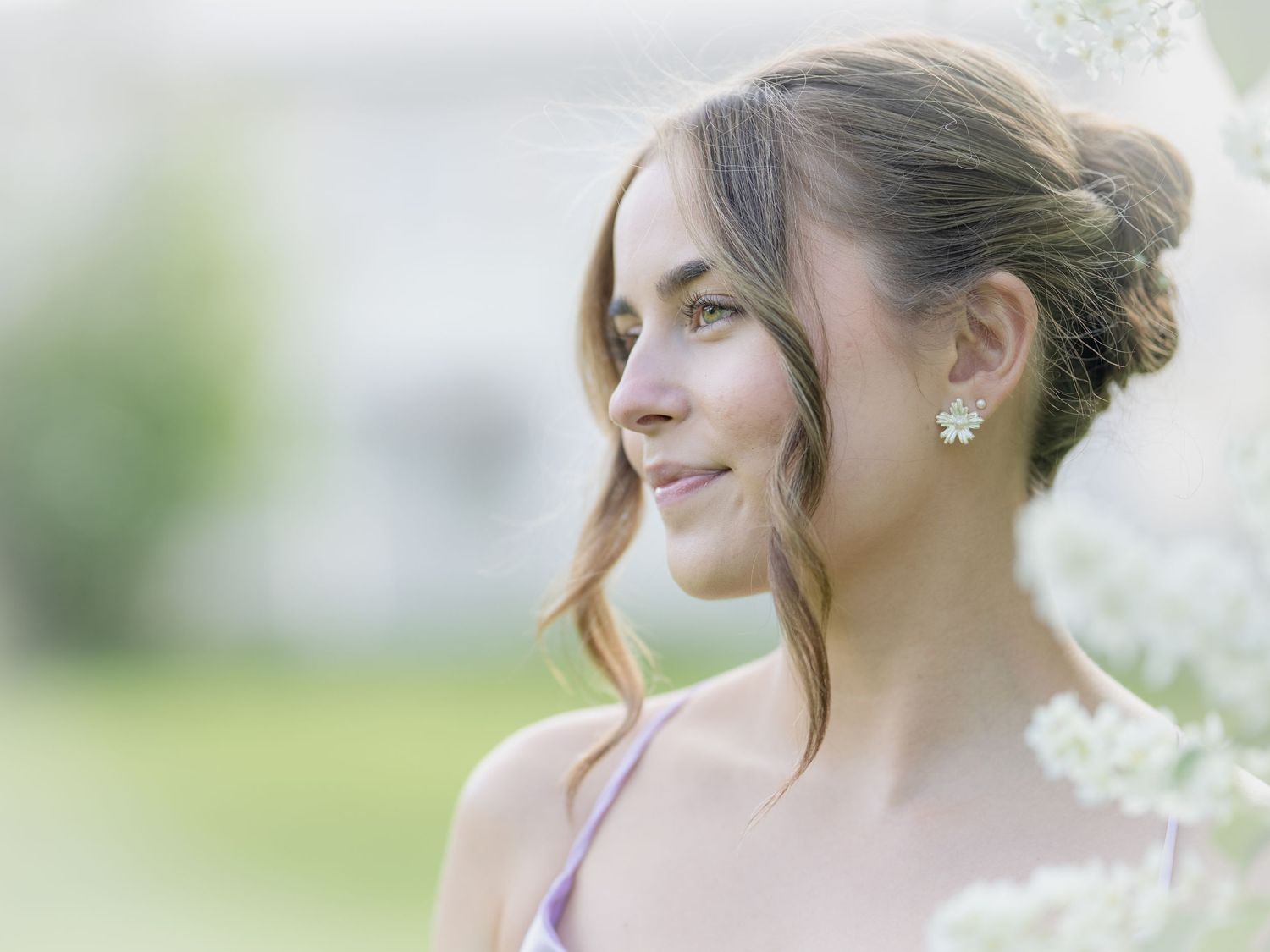 Elegant bridal portrait details with delicate earrings and soft focus florals in the background.