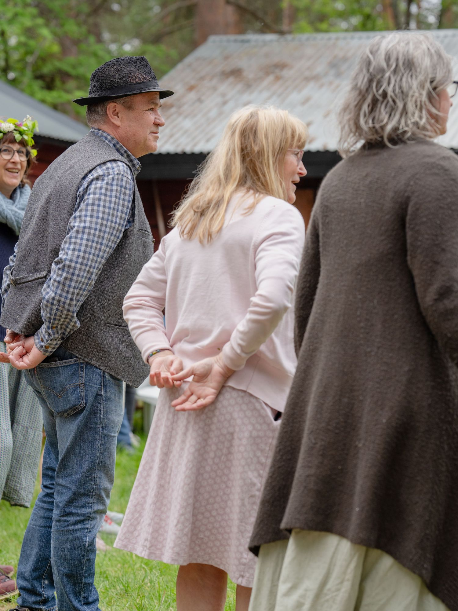 A group of people gather outdoors in casual attire including a person wearing a black hat and checkered shirt.
