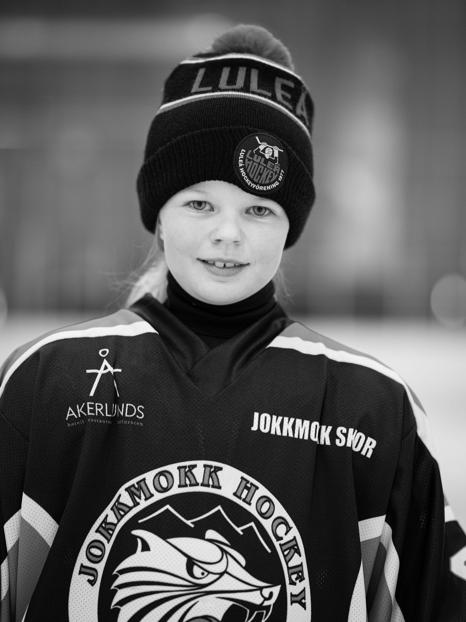 Ungdomshockeyspelare klädd i svart Luleå vintermössa och lagtröja i svartvitt porträtt.