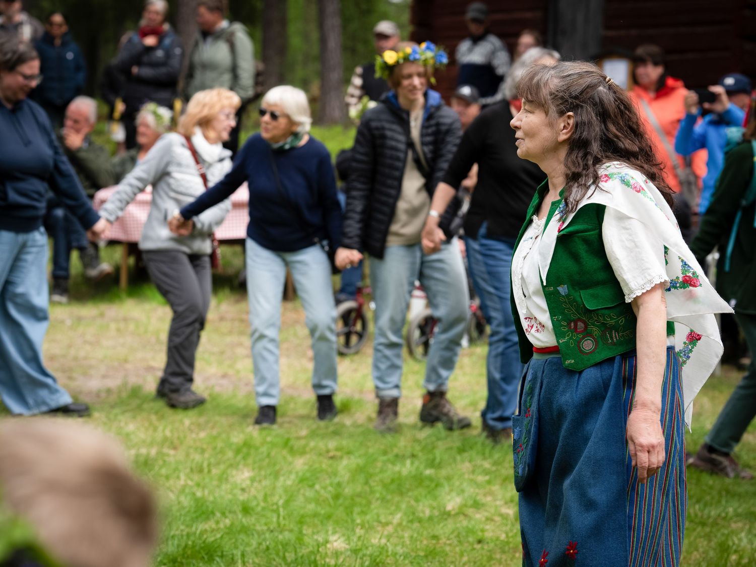 A large crowd gathers outdoors on a grassy area during what appears to be a community event or gathering.