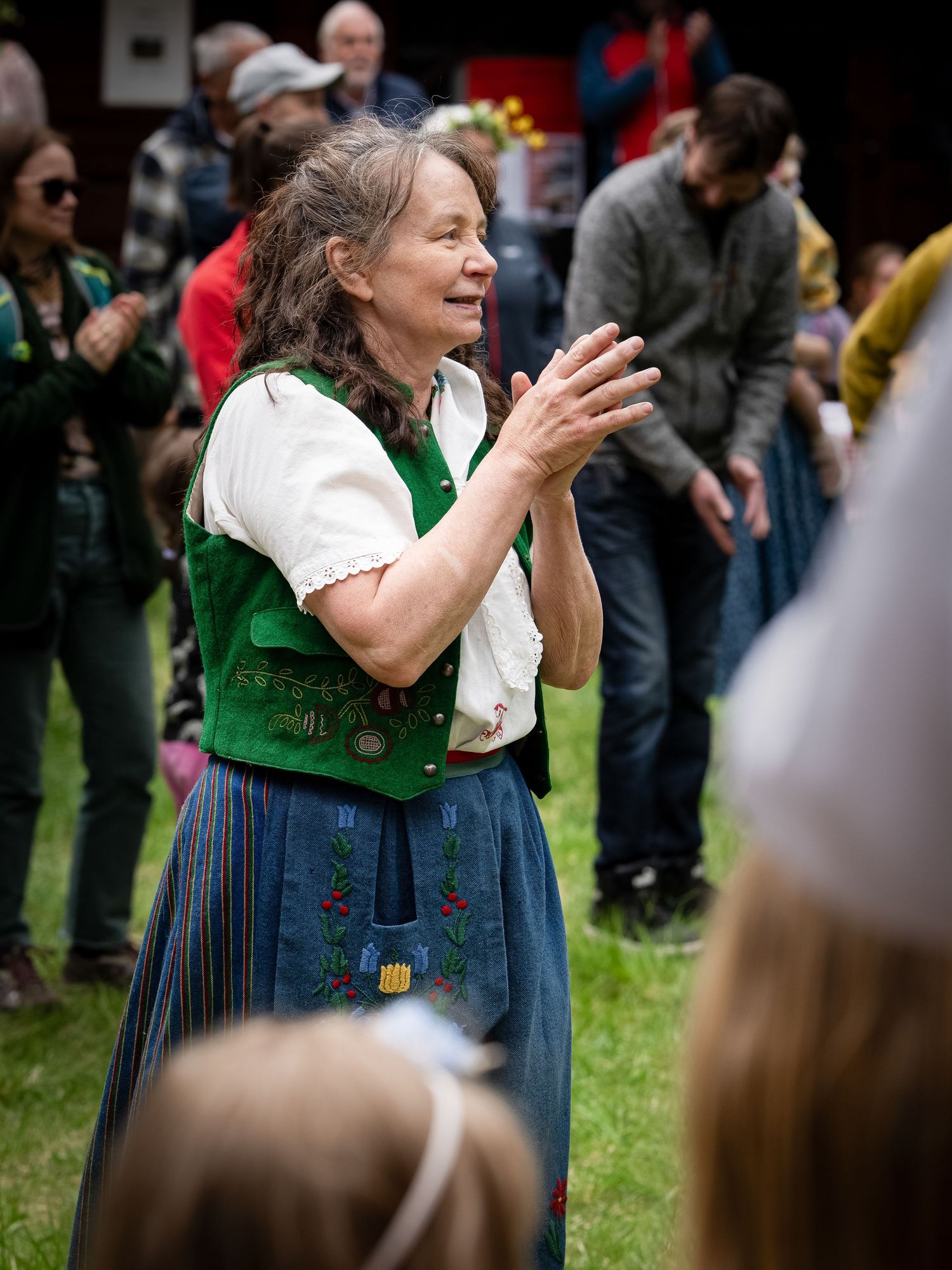 Woman wearing traditional German dirndl dress dances joyfully at outdoor festival celebration.