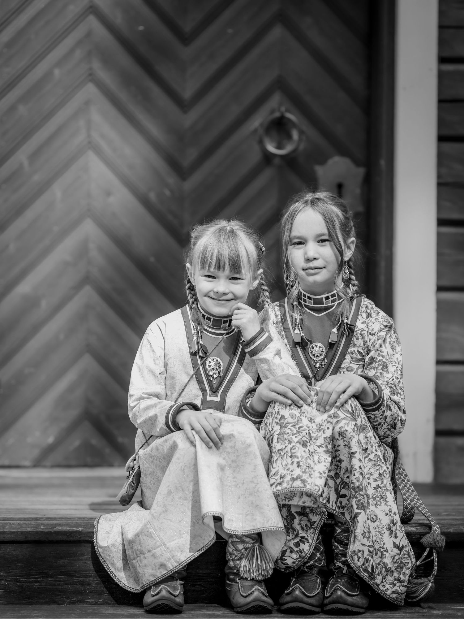 Två unga figurer i traditionella folkdräkter sitter tillsammans och delar ett glädjefyllt ögonblick.