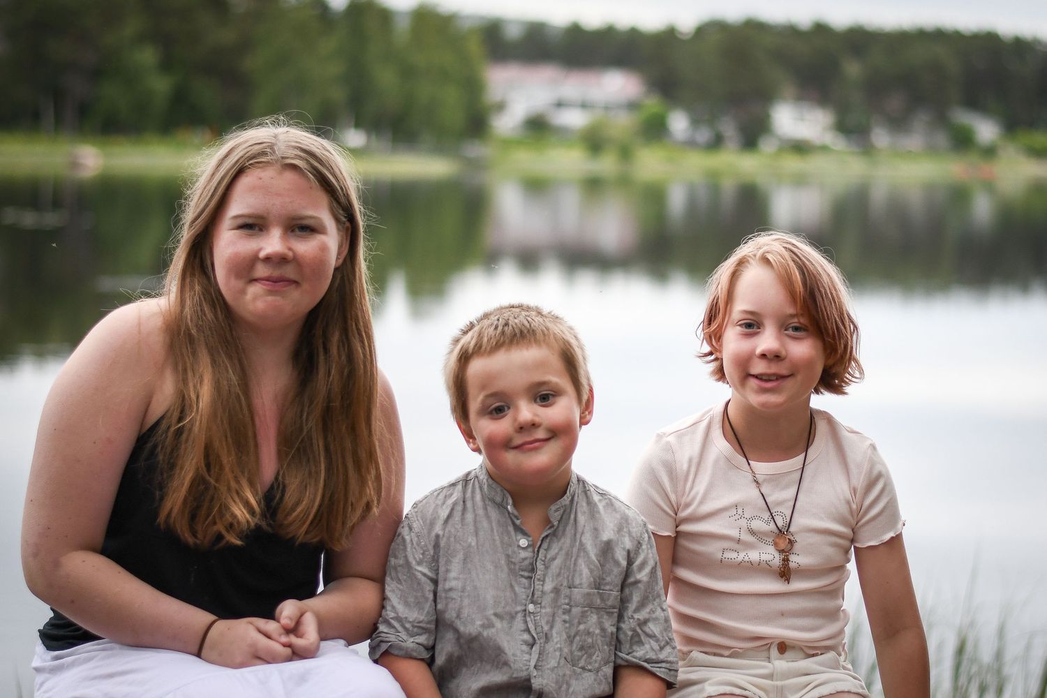 Familjegrupp sitter tillsammans vid sjön en solig dag.