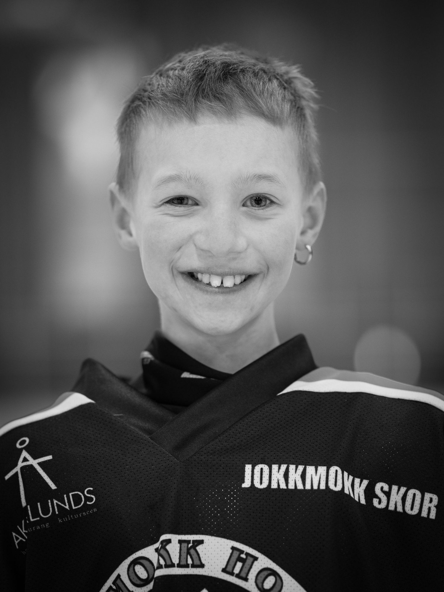 Ung hockeyspelare klädd i Jokkmokk Skor-tröja i svartvitt porträtt.