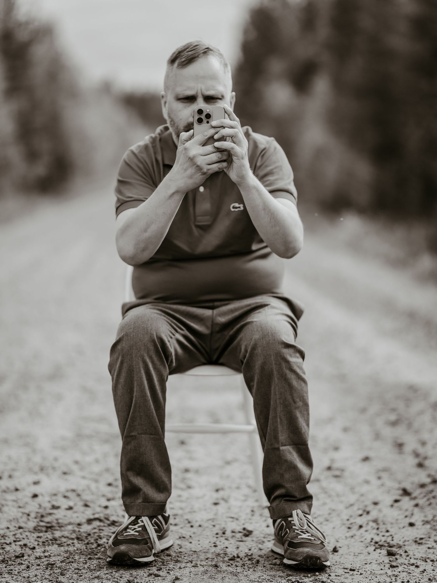 Black and white series of progressively closer shots of a seated figure on a gravel path in a dark setting.