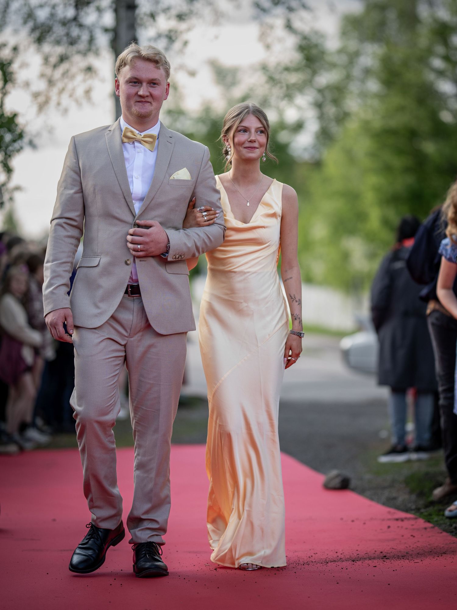 Par går nerför röda mattan vid formellt utomhusevenemang.