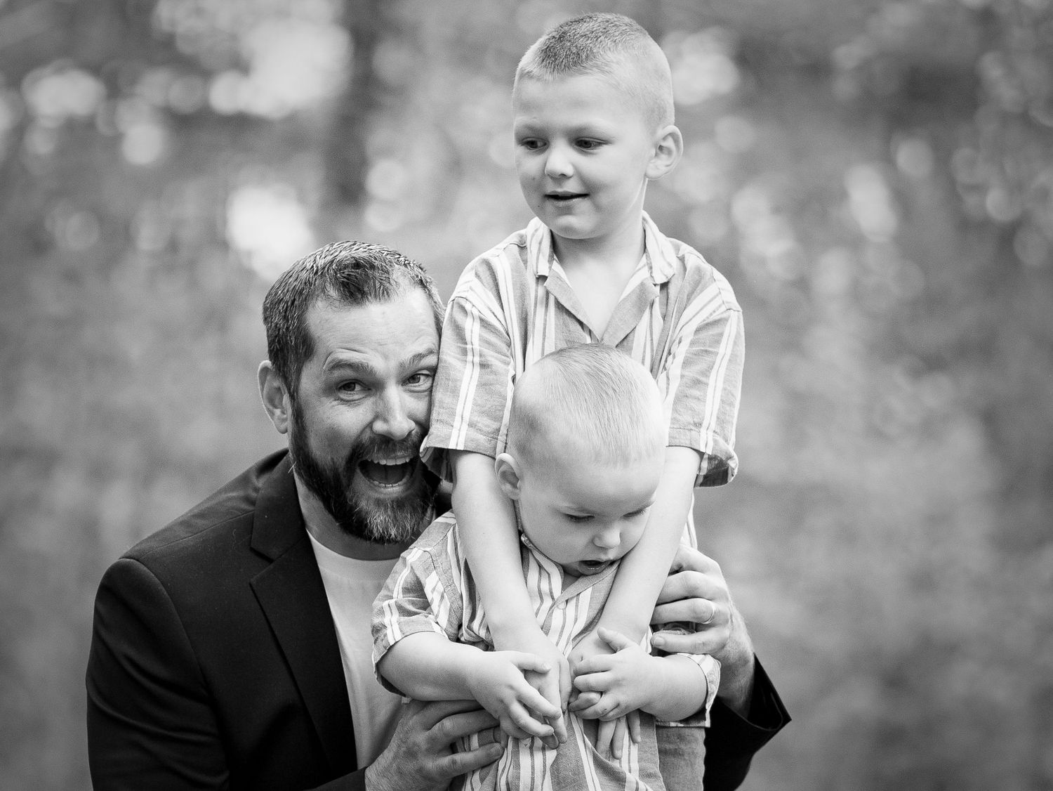 Svartvitt porträtt av familjemedlemmar som delar en lekfull stund utomhus.