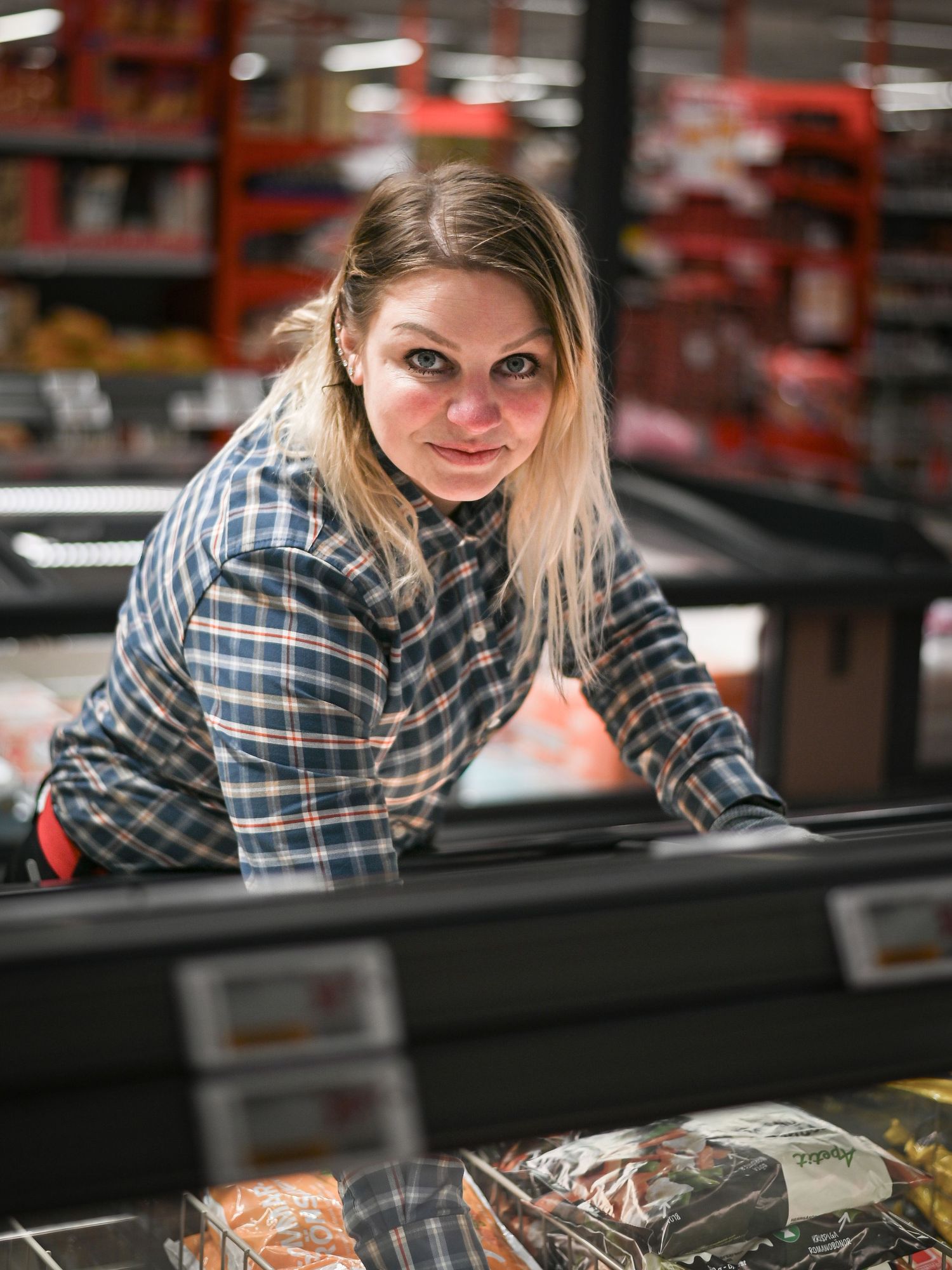 Person i rutig skjorta tittar ner på en frysmonter i mataffären.
