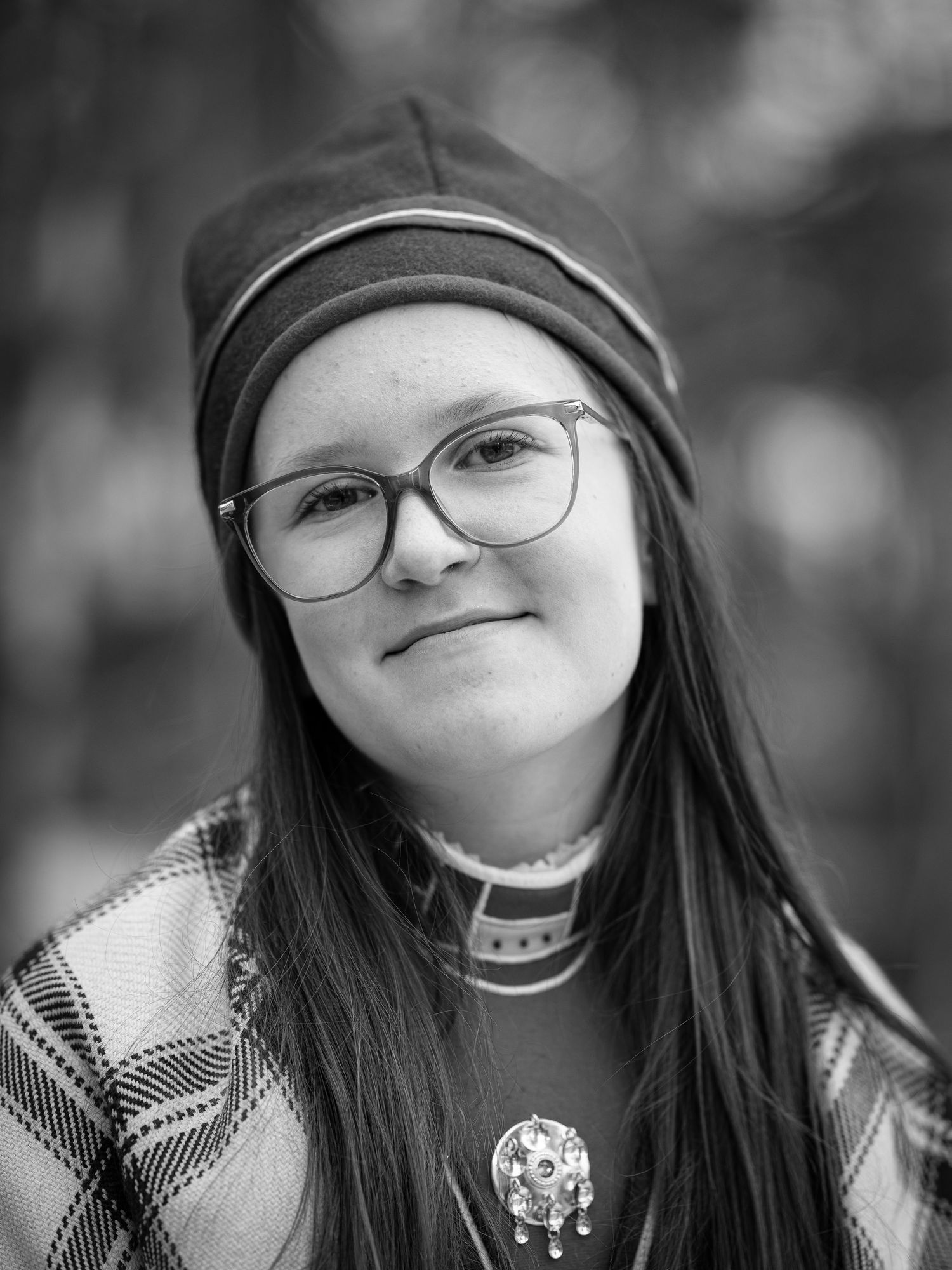 En serie svartvita porträttfoton som visar uttryck av glädje och skratt genom leenden och glasögon. Samisk kolt.