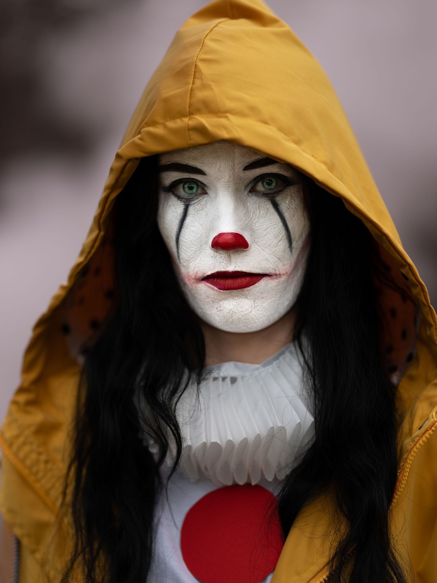 Närbild av gotisk clownsmink med gul huva och röd prickig kostym.