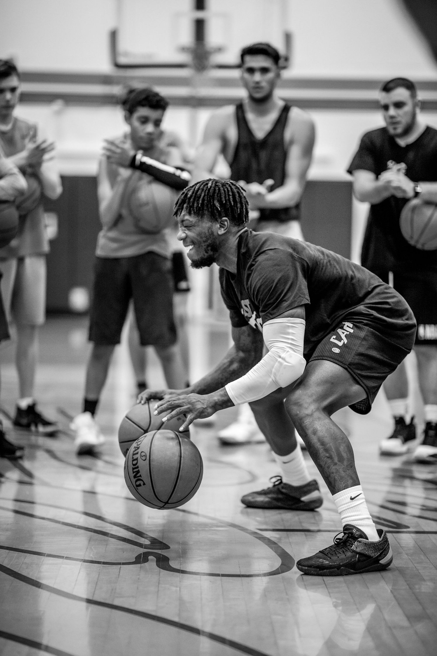 Basketball player dribbles ball during practice session in black and white photography.