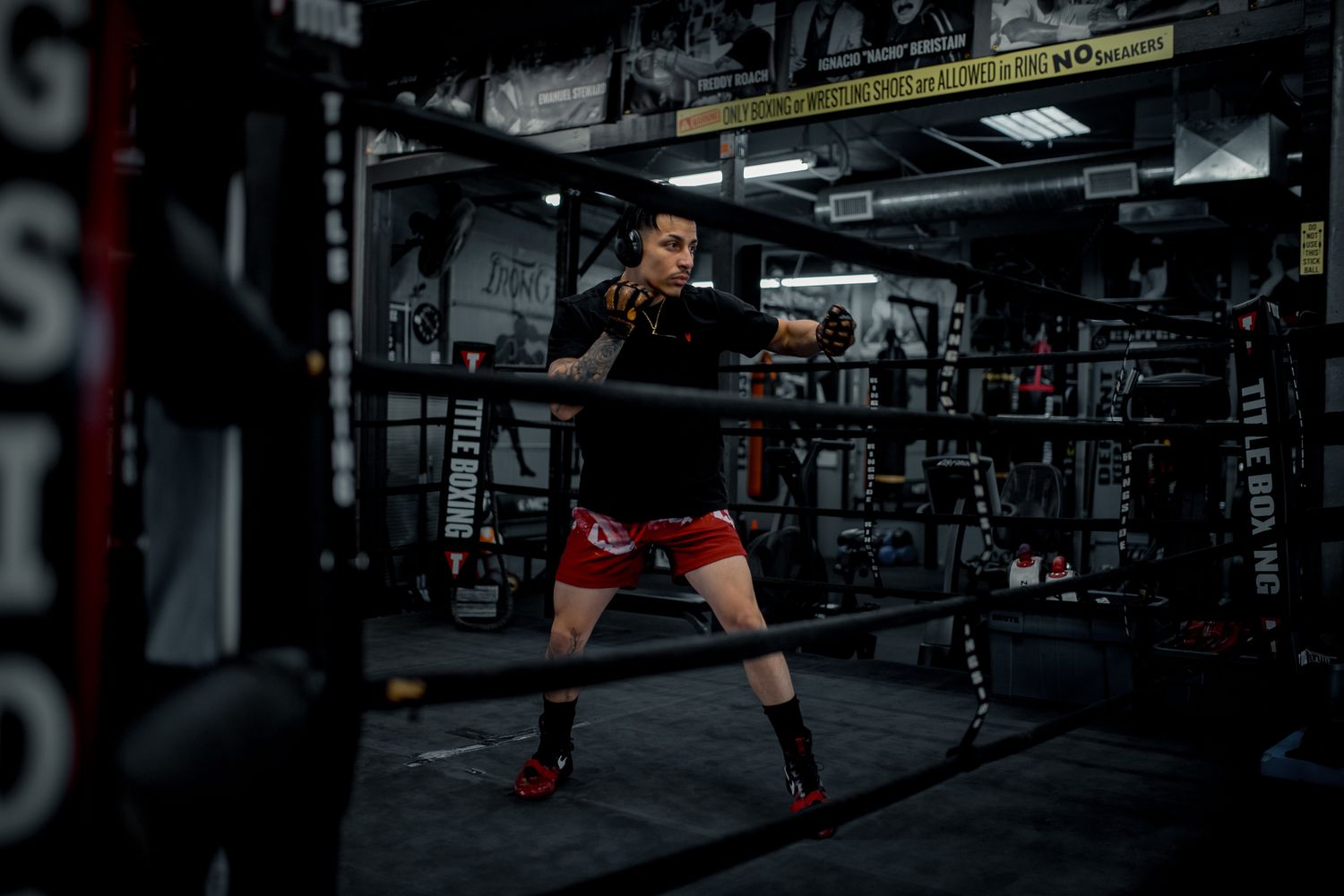 An athlete trains with resistance bands in a dimly lit boxing gym setting.