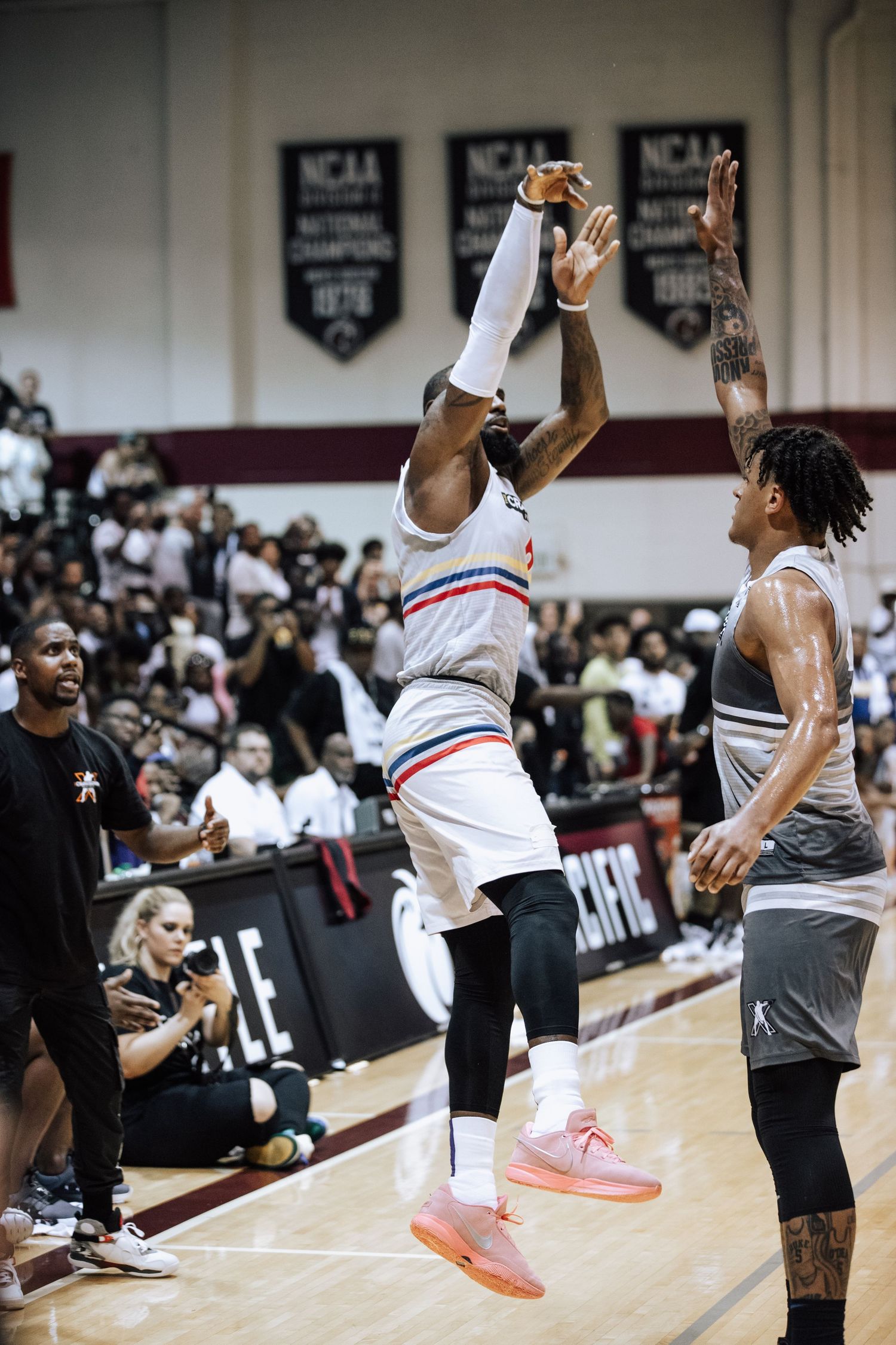 Basketball player in white uniform jumps high for shot during indoor game.