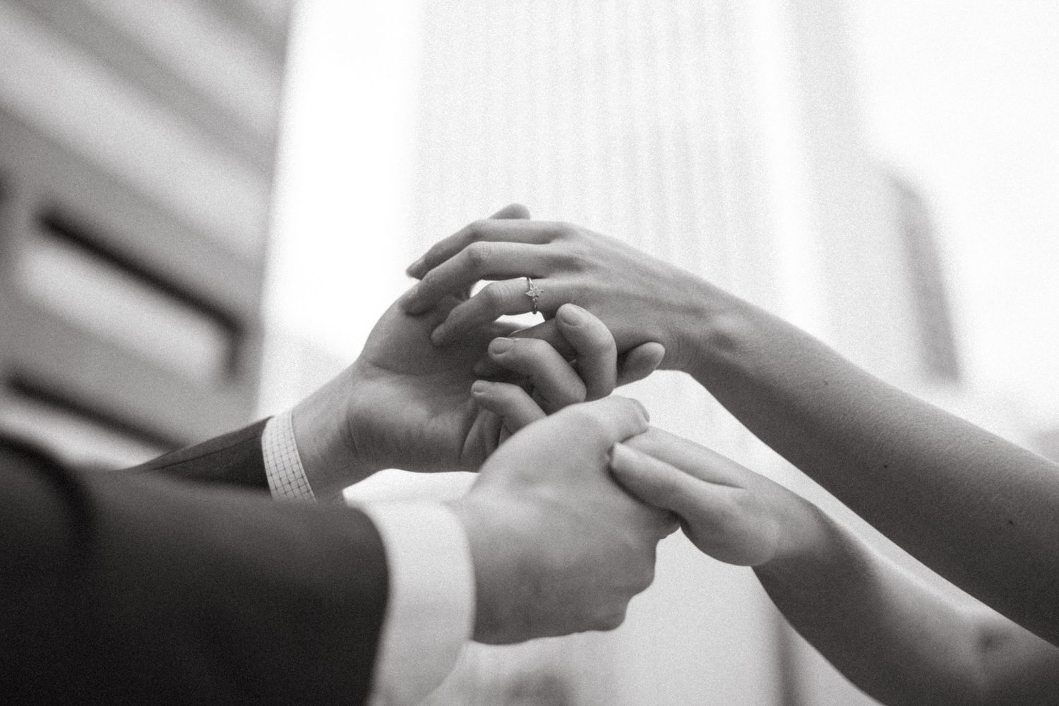 Black and white close-up of hands tenderly touching in an intimate moment showing care and connection.