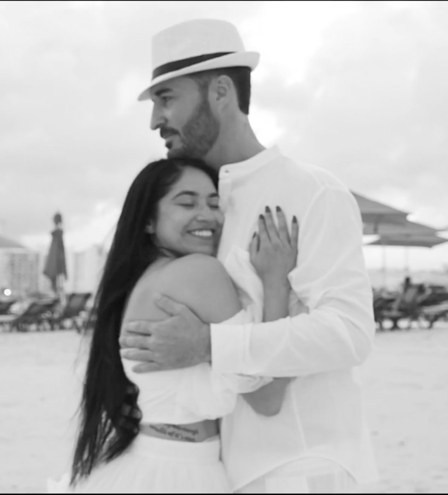 Romantic black and white beach photoshoot of couple in white attire.