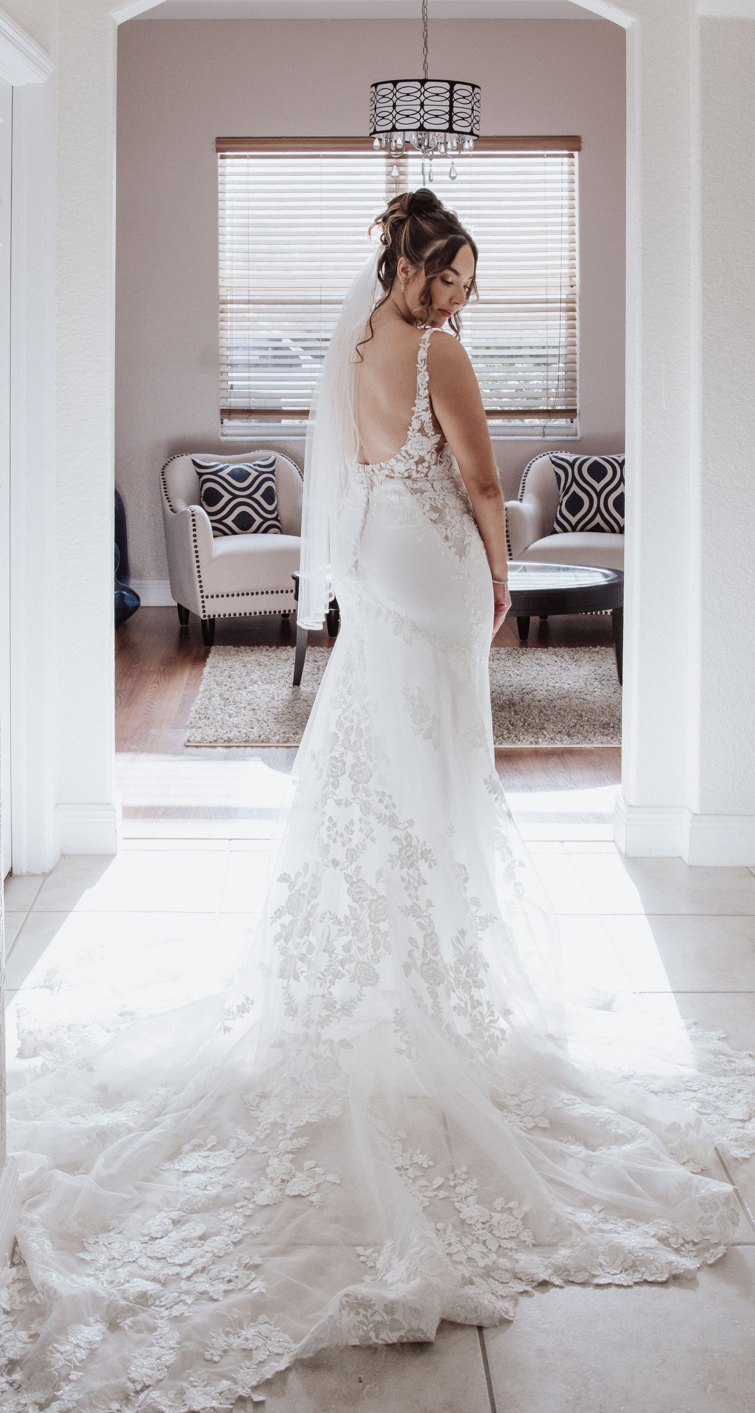 Back view of lace wedding dress with dramatic train in elegant room setting.
