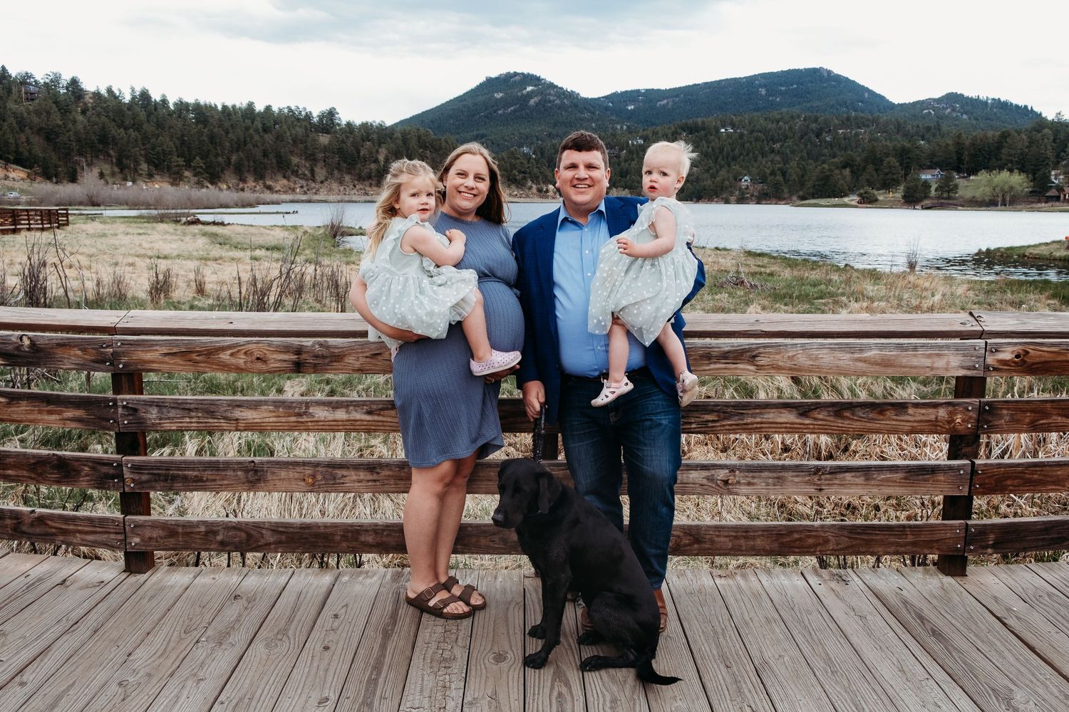Family of four with black lab at Evergreen Lake House, mountain views in background.