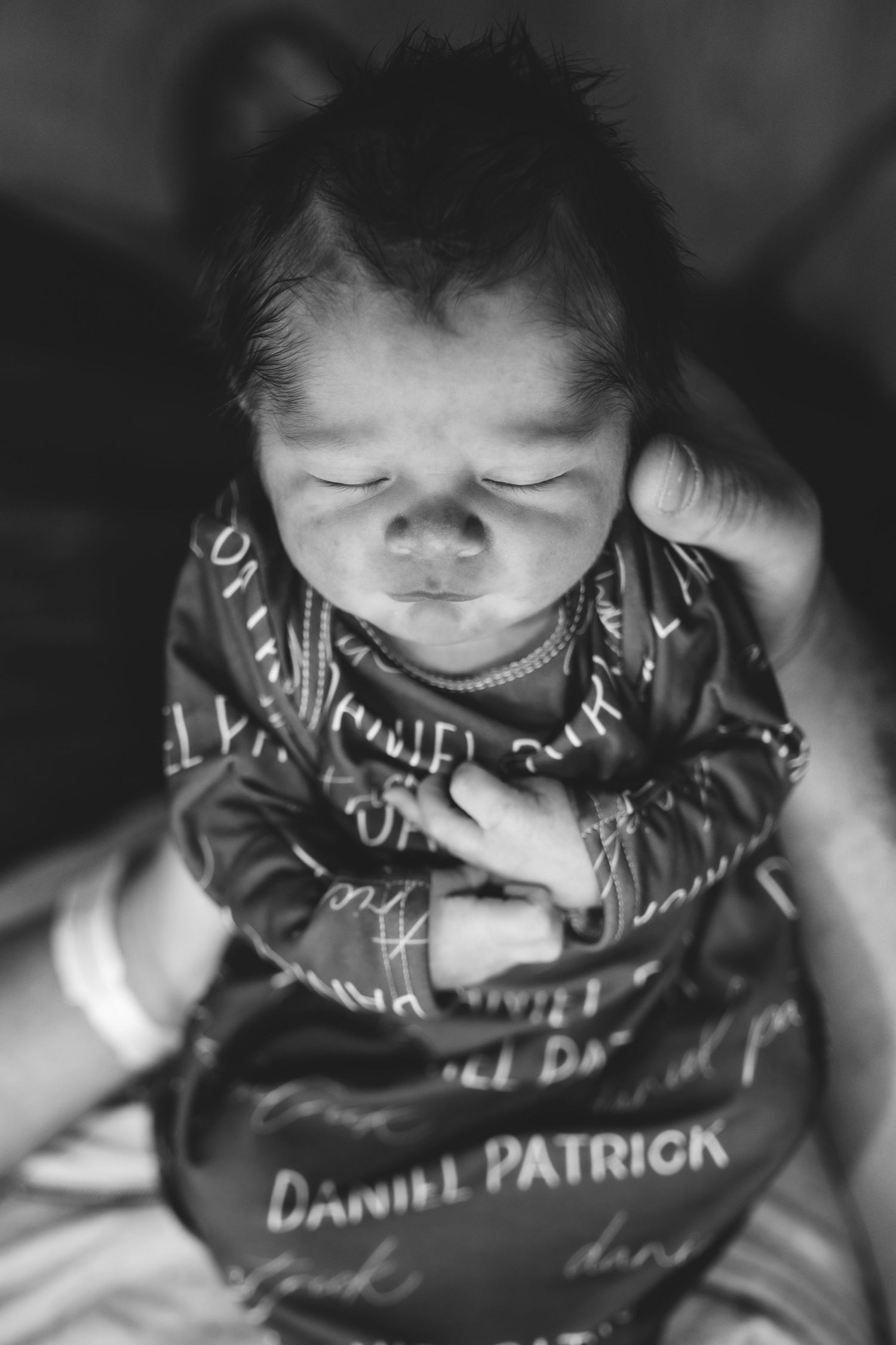 Black and white portrait of baby newborn baby sleeping with serious expression.