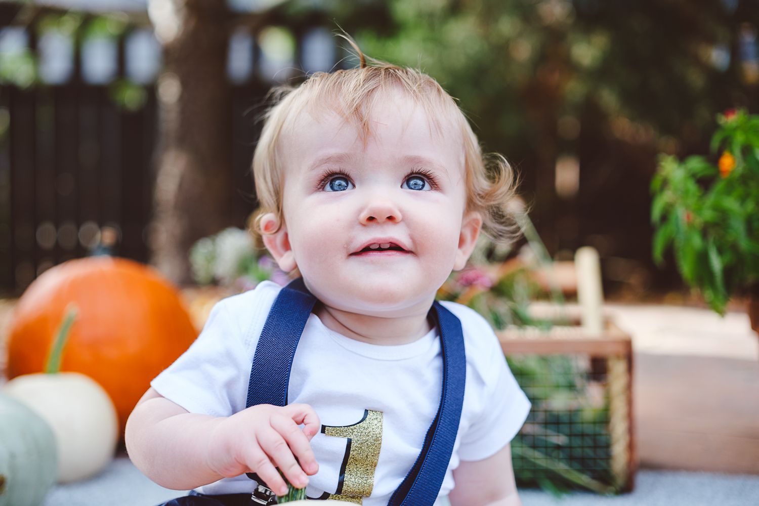 Close up of one year old boy, he has a soft smile and a curious expression.