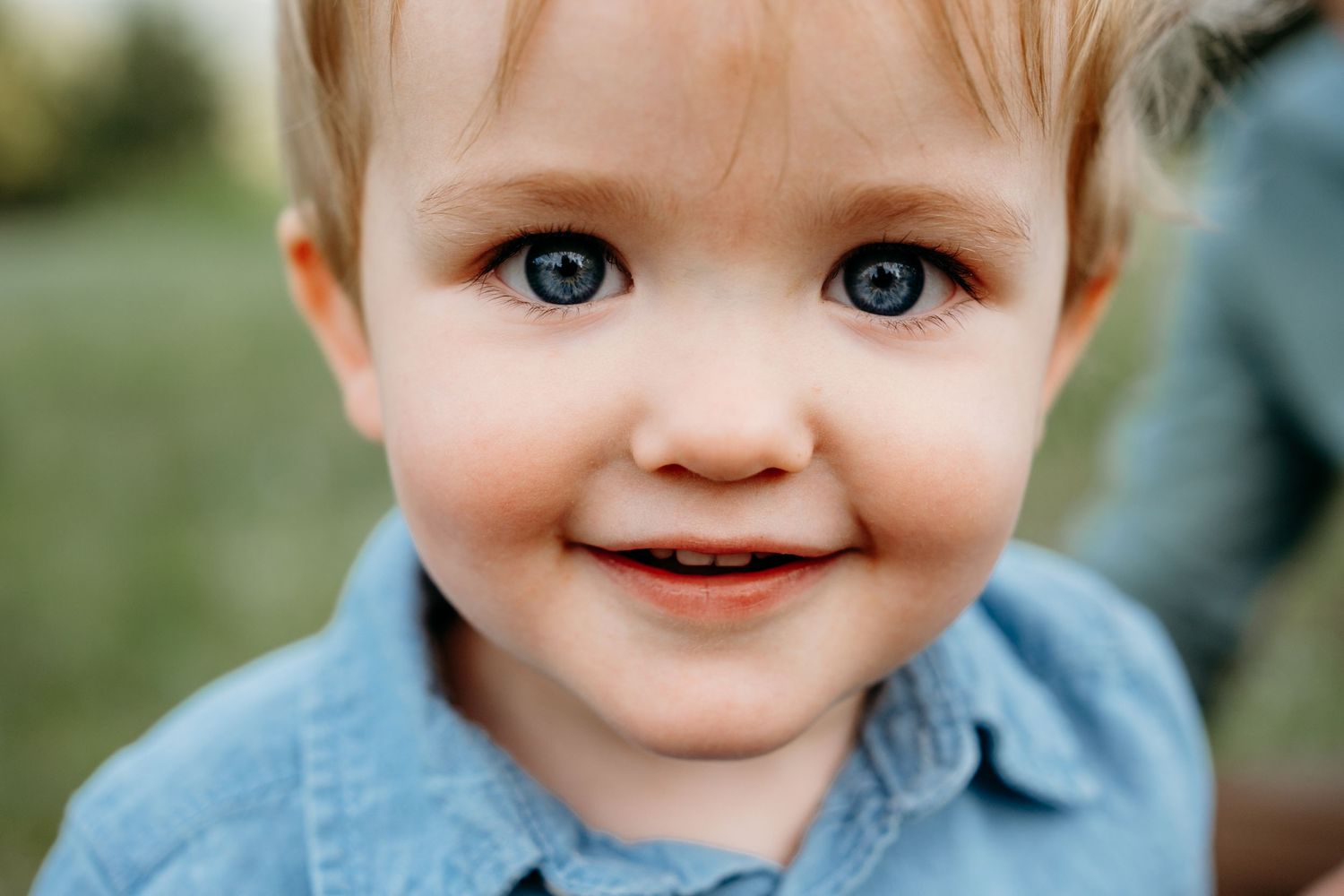 Close up of smiling young boy with big, bright blue eyes.