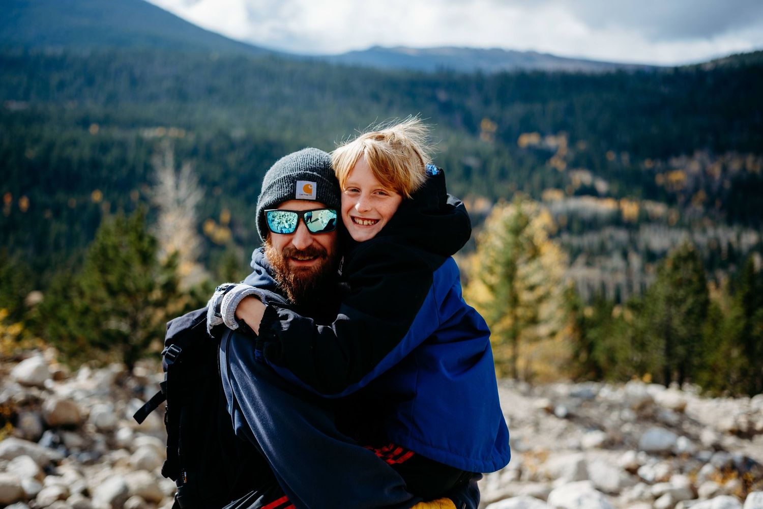 Husband holding son at rocky area of Alluvial Fan in RMNP.