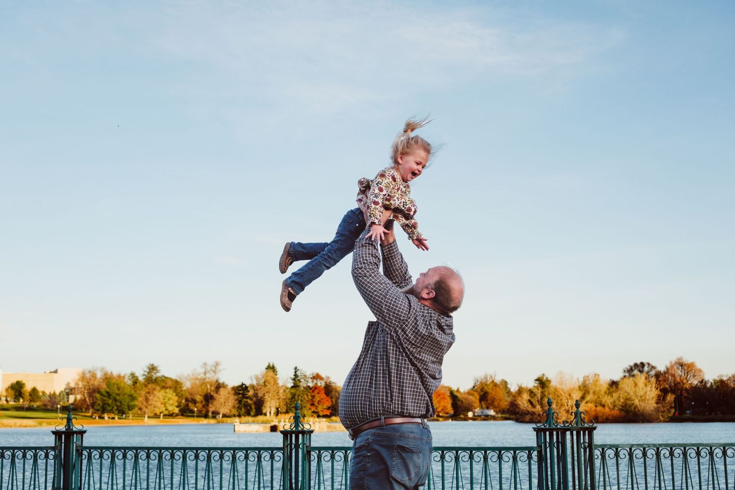 Father tossing toddler daughter into air, Ferrill Lake in the background.