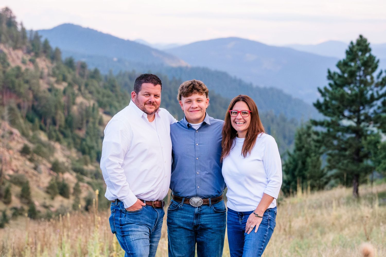Mother and father standing with their teenage son at Mount Falcon west, mountains in background.
