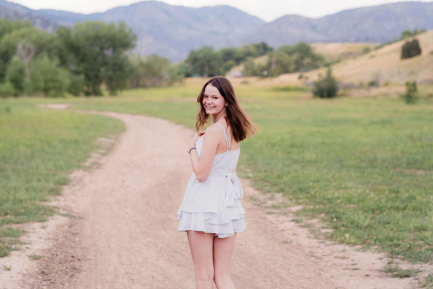 Teen girl walking on dirt path, peering over her shoulder.