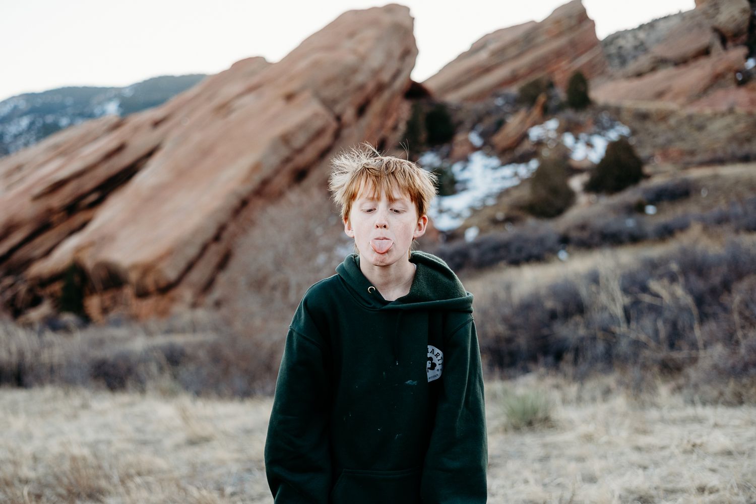 Boy playfully sticking out his tongue, red rocks in background.