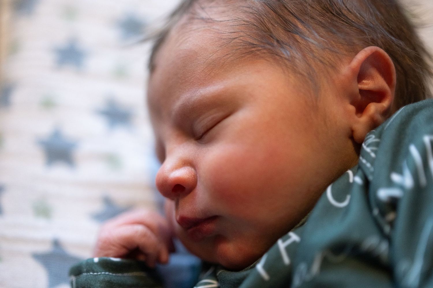 Close up of newborn's face, sleeping in hospital bassinet.