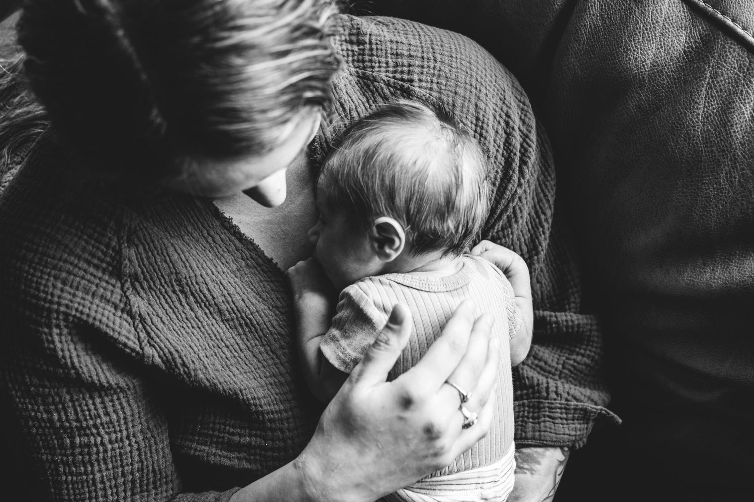 Overhead of mother snuggling newborn to her chest.
