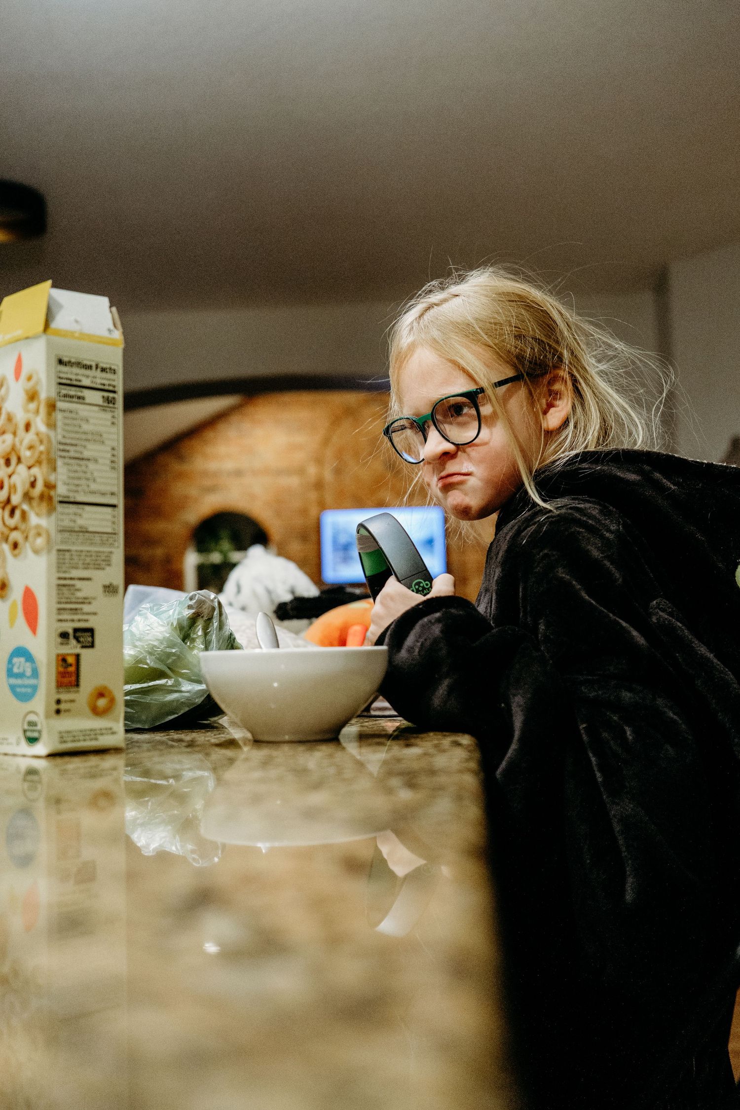 Girl sitting at counter eating breakfast, making silly face.