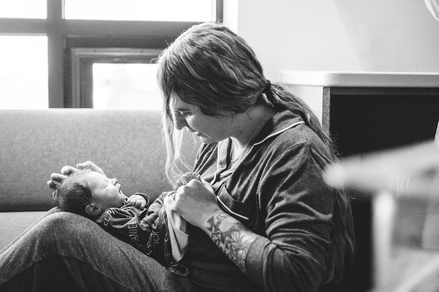 Black and white profile of mother cradling newborn baby in her lap in Fresh 48 session.
