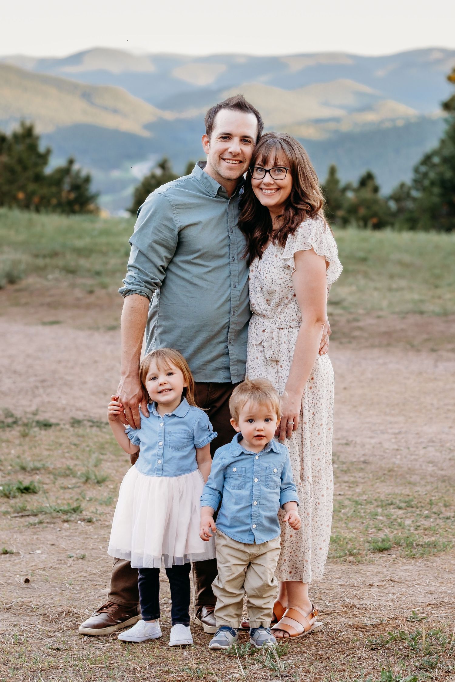 Mother and father standing, toddler son and young daughter standing in front of them, all smiling.