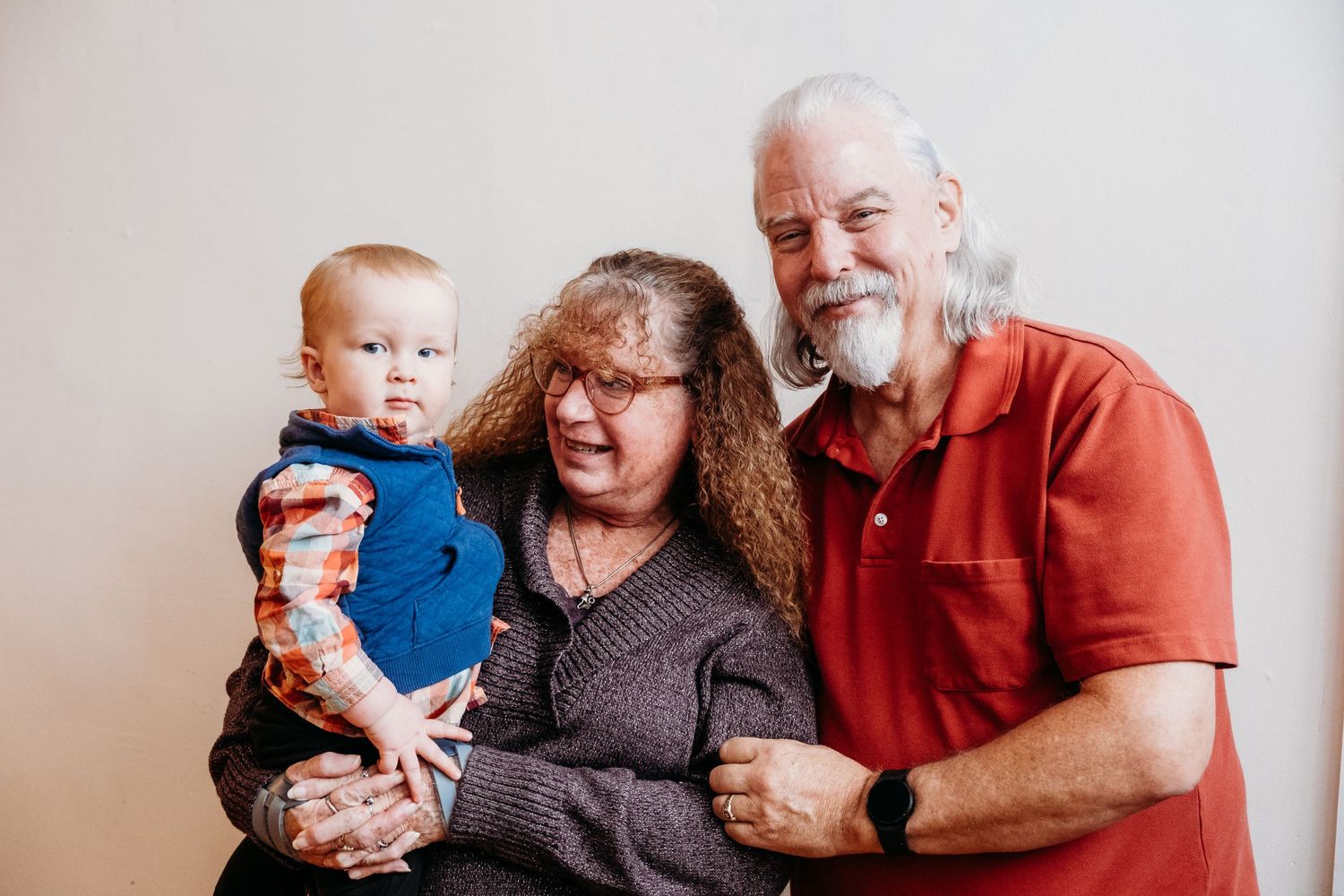 Grandparents holding toddler son in in studio family portrait session.