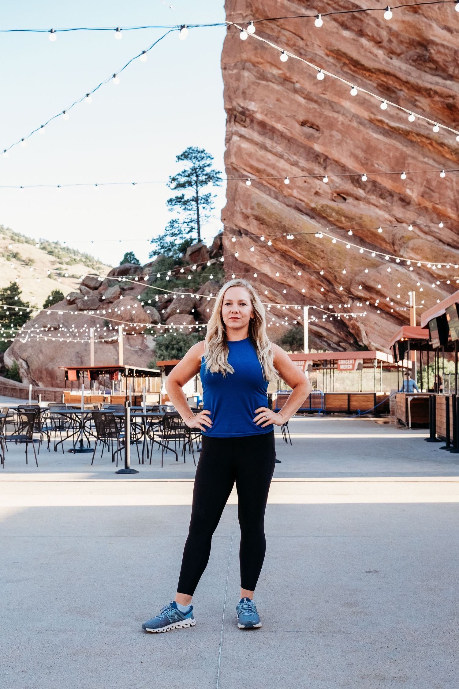 Fitness branding photography with female trainer standing in power pose at top of Red Rocks Amphitheater.