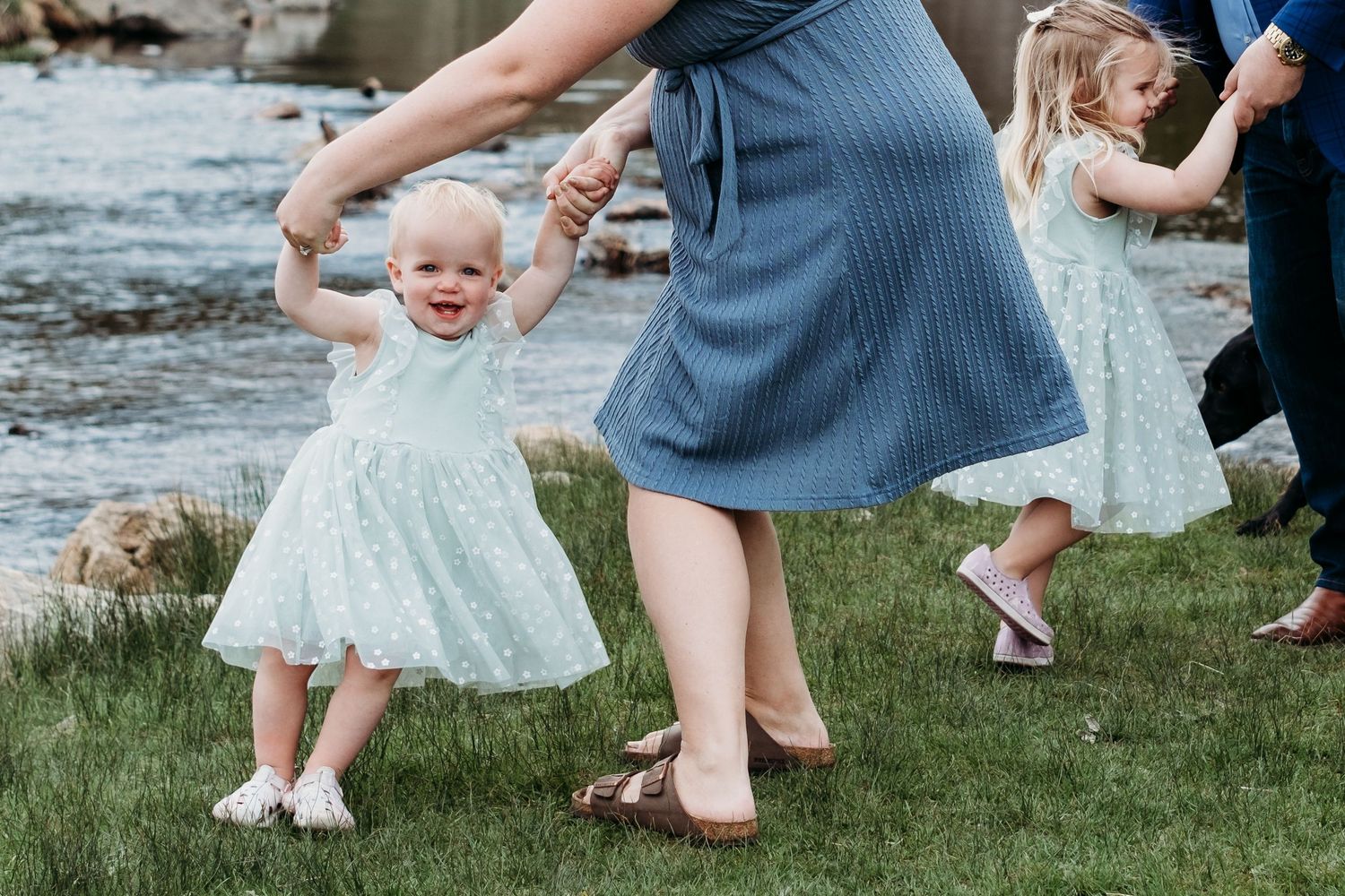 Mother twirling toddler daughter, father twirling big sister in background.