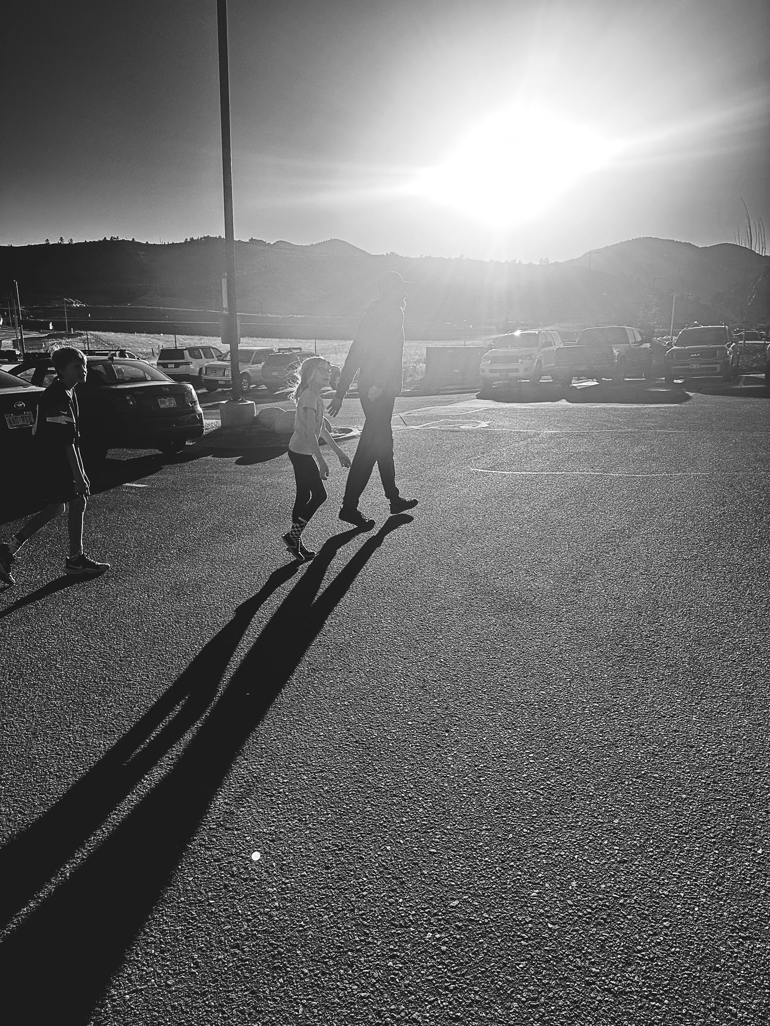 Denver photographer project 365 - black and white of family walking, sun making harsh sun flare, long shadows on the ground