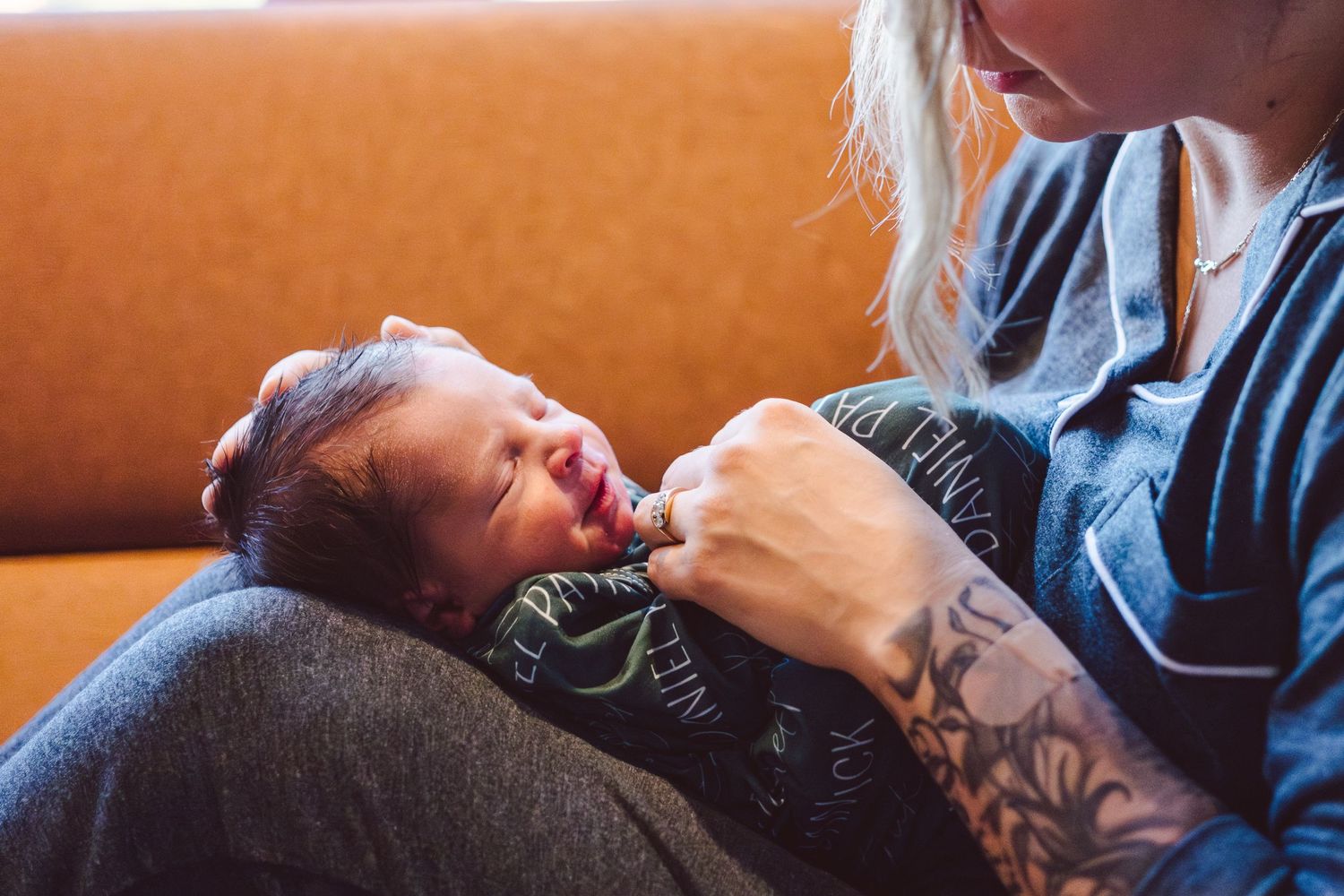 New mother holding balancing her newborn on her bent legs, holding him delicately.