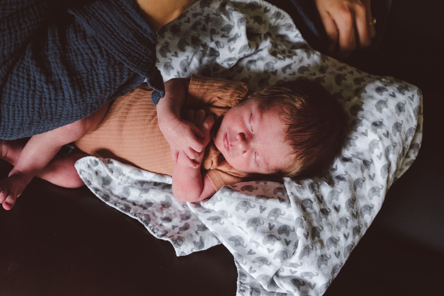 Newborn boy sleeping on mother's lap.