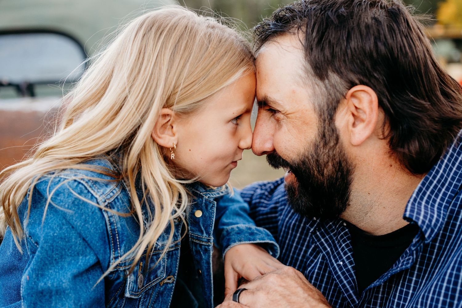 Father and daughter touching foreheads, nose-to-nose, smiling.