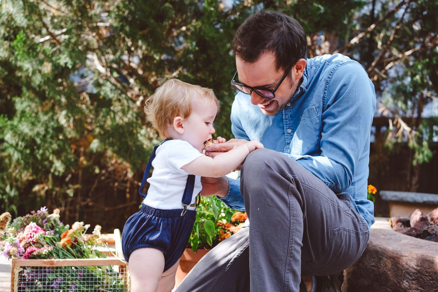 Dad feeding one year old son cake from his cake smash.