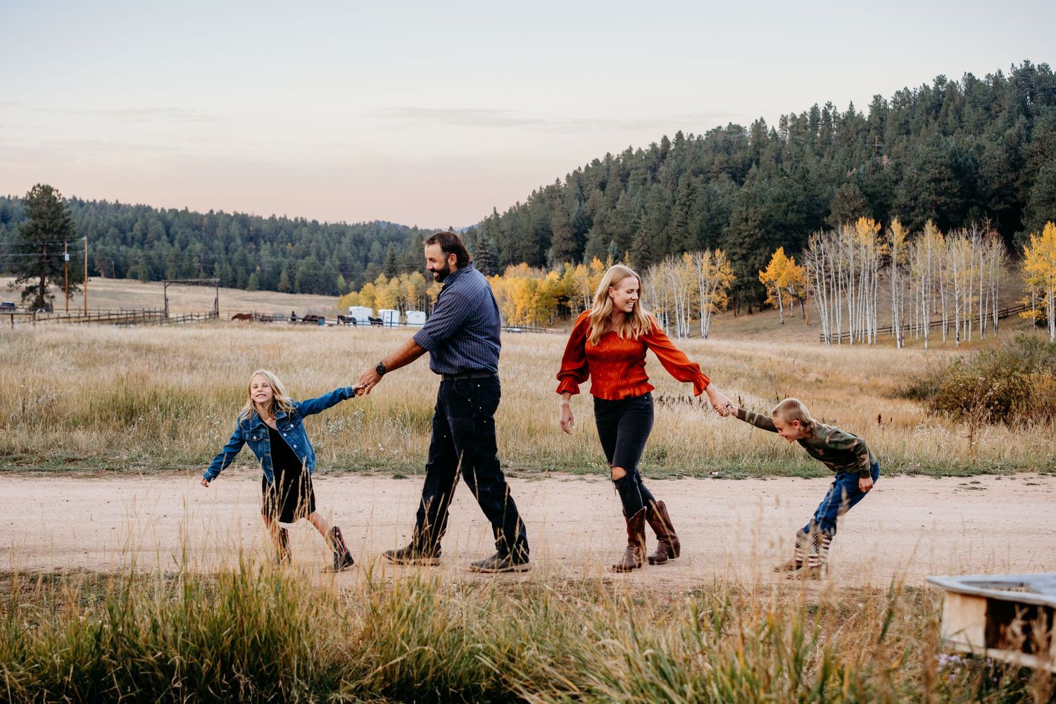 Daughter pulling father playfully forward while so playfully pulls mother backward. Mother and father laughing.