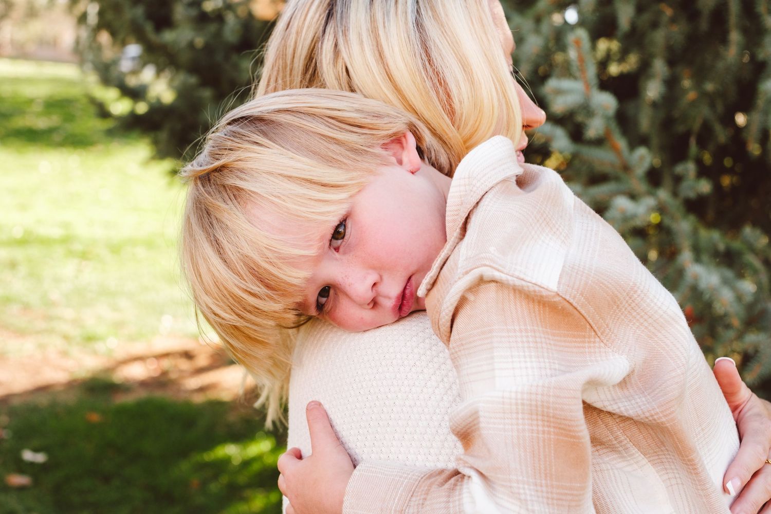 Young boy snuggling on shoulder of mother.