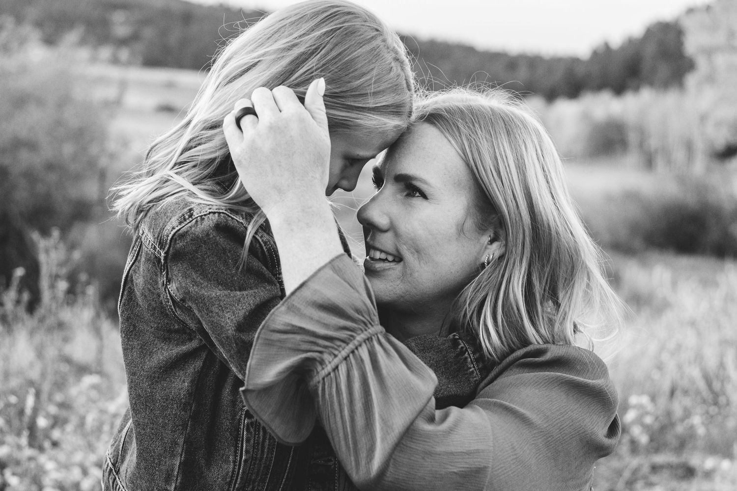 Mother delicately smoothing hair of daughter behind her ear.