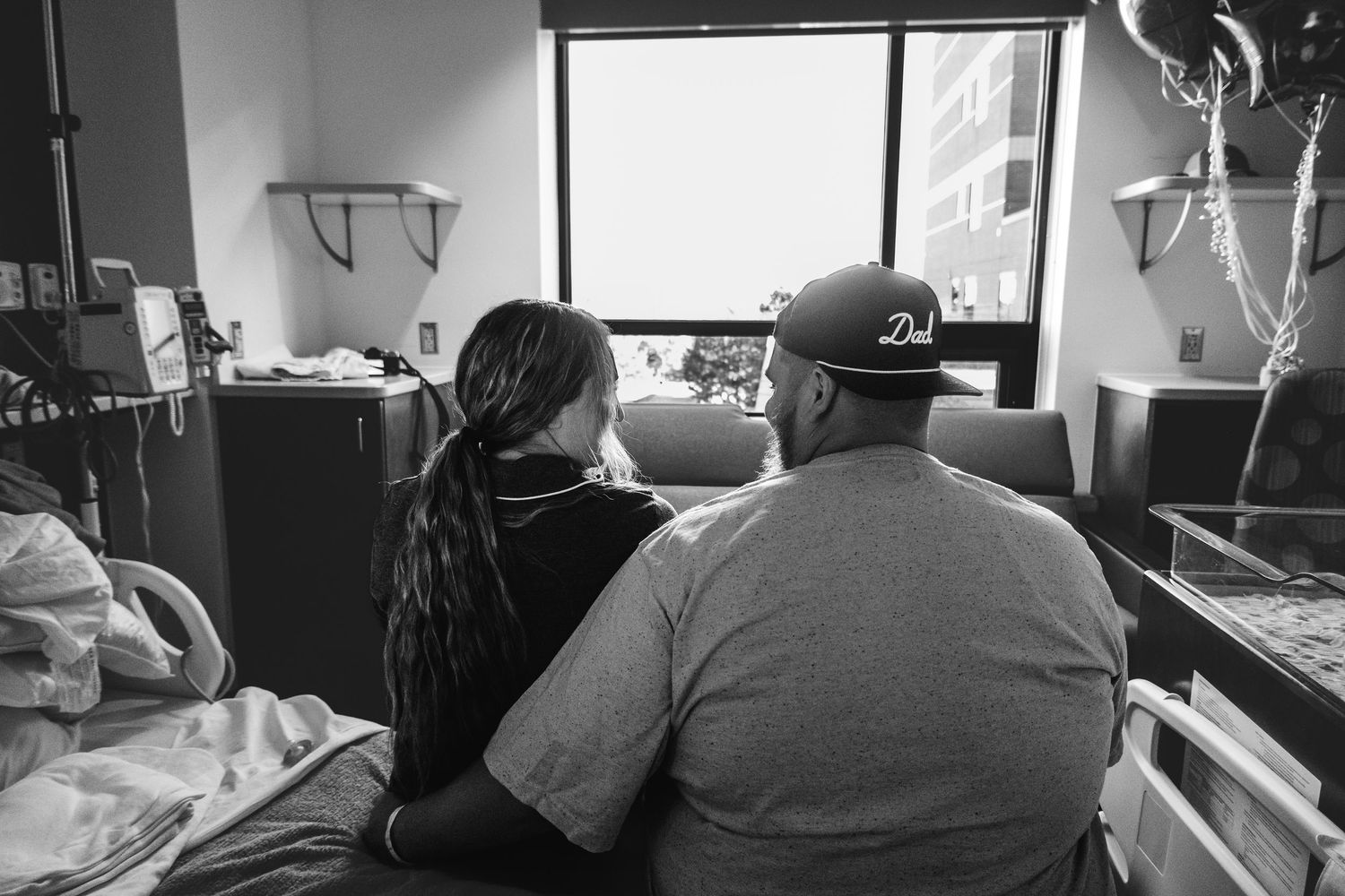 Mother and father sitting on hospital bed in Fresh 48 session.